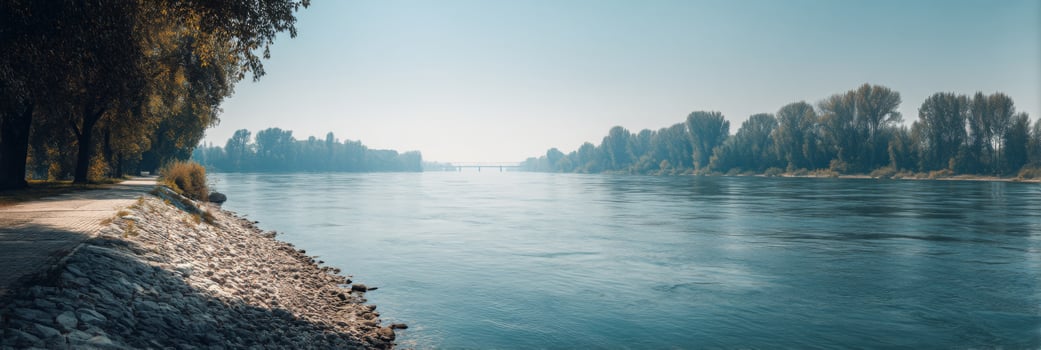 Serene Riverbank Landscape with Clear Water Reflection and Lush Green Trees Alongside a Peaceful Walking Path photo