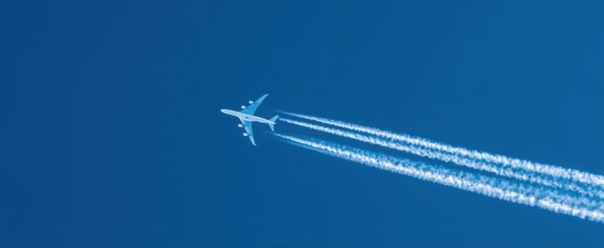 The airplane soaring through a vibrant blue sky, leaving a trail of contrails. photo