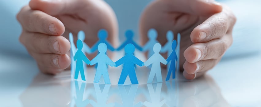The hands protecting a group of paper cutout figures in unity. photo