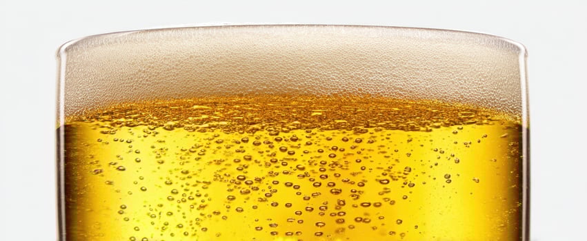 The glass of refreshing beer filled with golden bubbles and frothy foam. photo