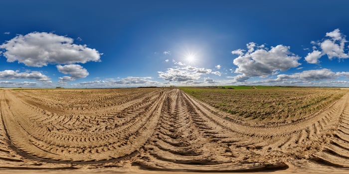 A 360 - view of a field with dirt and clouds photo