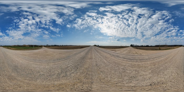 A 360 - view of a dirt road with clouds in the sky photo