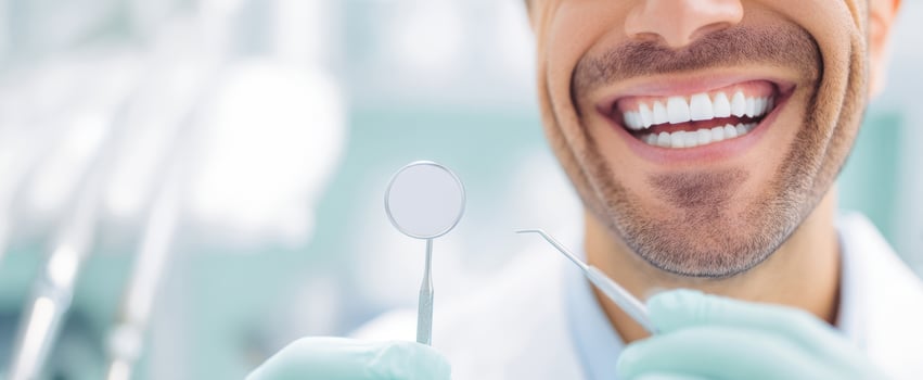 The dentist holding instruments and showcasing a bright, confident smile photo