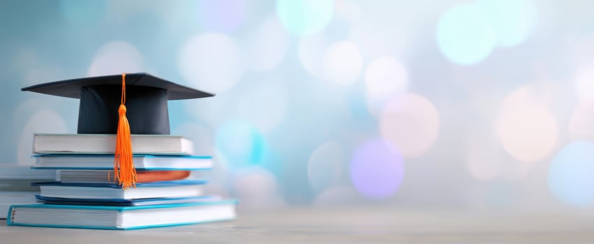 The graduation cap atop a stack of books with a dreamy blue background. photo