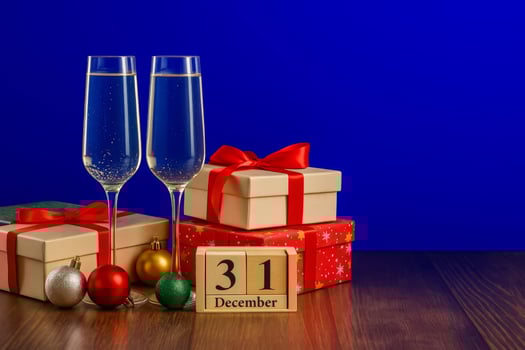 Champagne glasses and wrapped gifts for New Years Eve party. holiday gift boxes tied with red ribbons, colorful Christmas baubles photo