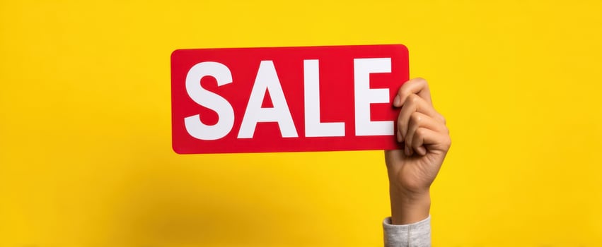 The hand holding a red sale sign against a vibrant yellow background. photo