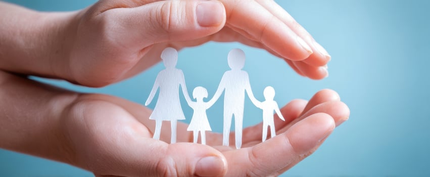 The hands cradling a paper family symbolizing love and protection. photo
