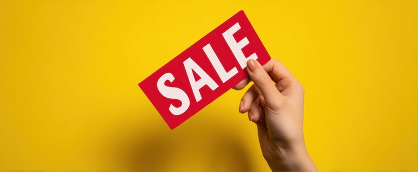 The hand holding a vibrant sale tag against a bright yellow background photo
