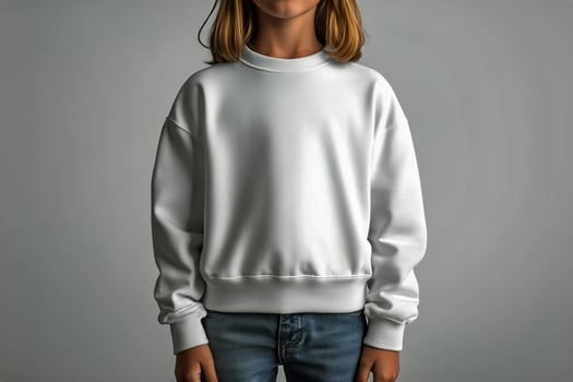 Child Wearing a Plain White Sweatshirt and Jeans Against a Neutral Background in a Studio Setting. photo