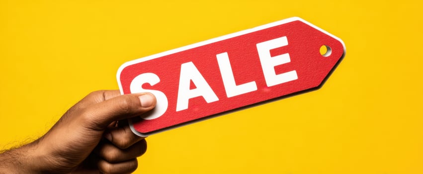 The vibrant sale tag held aloft against a bright yellow background photo