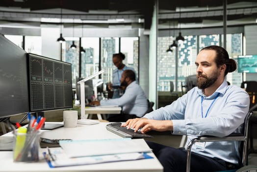 Day trader with paraplegia in wheelchair capitalizing on market fluctuations when buying and selling stocks. Person with disability in inclusive prop firm office identifying fast profit opportunities photo