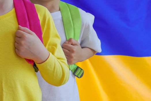 Two children with satchels background of Ukraine flag photo