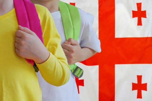 Two children with satchels background of Georgia flag photo