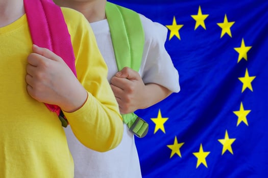 Two kids with satchels background of EU flag photo