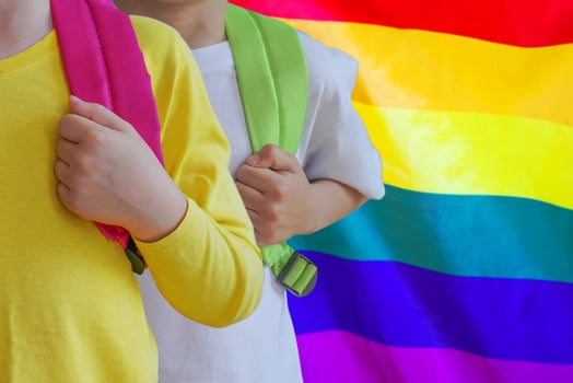 Two kids with satchels background of rainbow flag photo