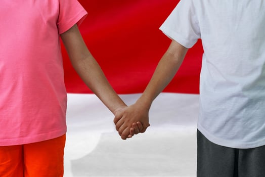 Boy and girl joined hands on background flag of Indonesia photo
