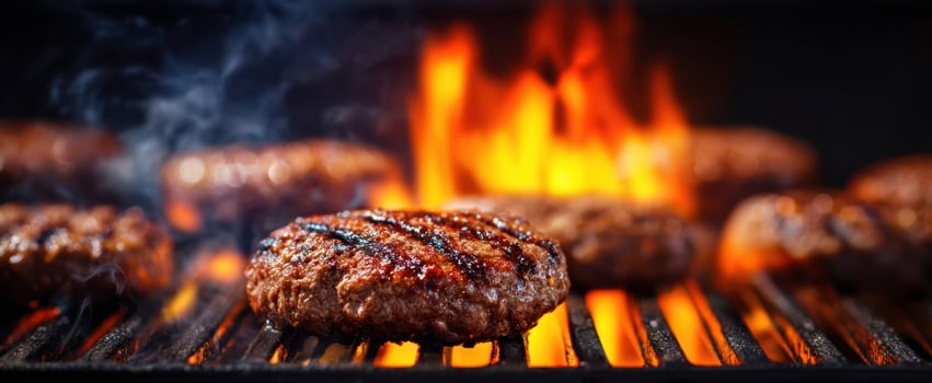 The Grilled Burger Sizzling Over Open Flames On A Charcoal Barbecue Grill photo