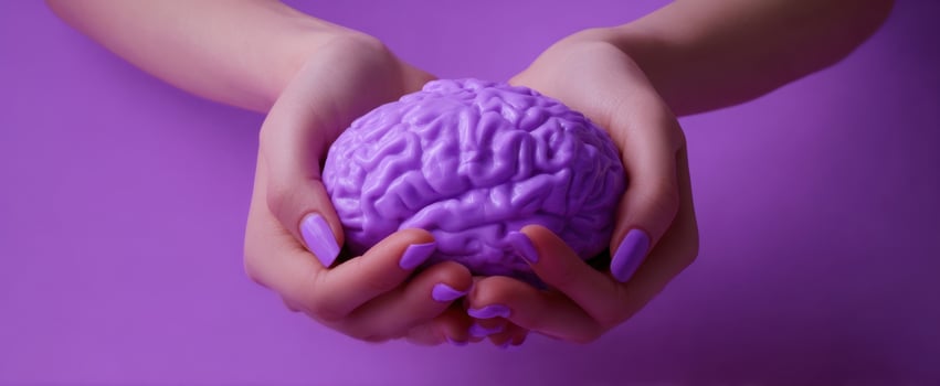 The Brain Held in Purple Hands Representing Creativity, Mental Health, Science, and Care photo