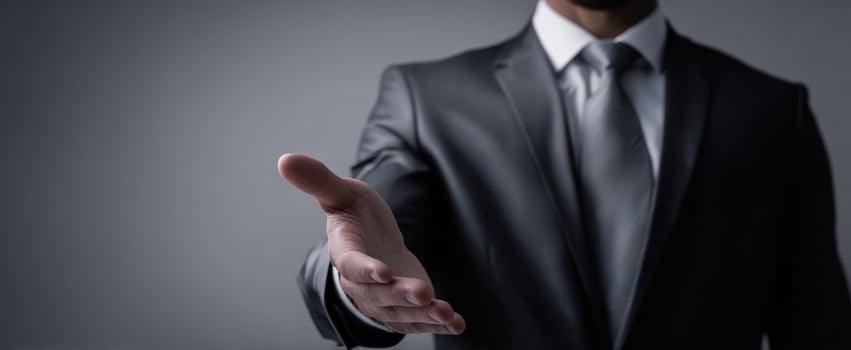 The businessman extending a welcoming handshake in a dark suit for partnership photo