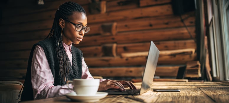 The woman working on a laptop at a rustic wooden table by window photo