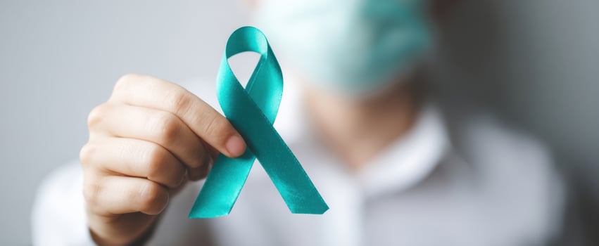 The teal awareness ribbon held by a masked healthcare worker in soft focus photo