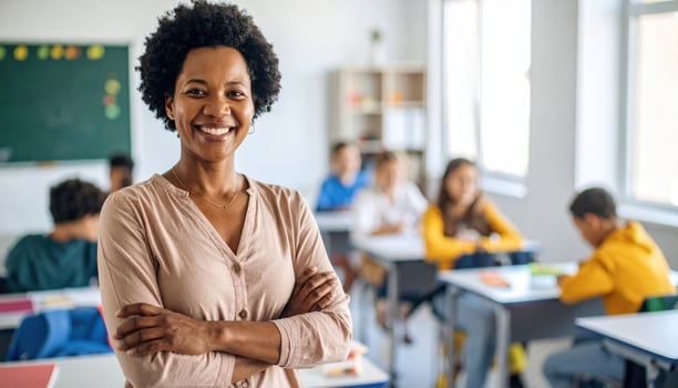 Confident woman stands in classroom, arms crossed, exuding authority and warmth. She smiles at camera, surrounded by students engaged in learning activities photo