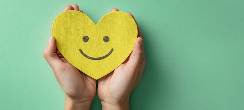 The Yellow Heart with Smiley Face Held Gently in Caring Human Hands photo
