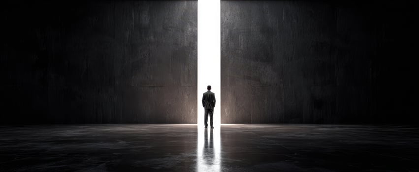 The man standing before a narrow vertical doorway of blinding white light photo