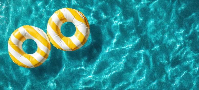 The Yellow Striped Inflatable Rings Floating on Sparkling Turquoise Pool Water in Summer photo