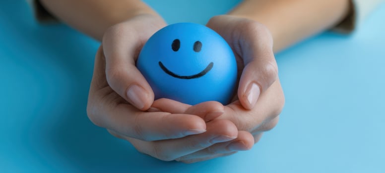 The Blue Smiley Stress Ball Cradled in Gentle Hands on Soft Blue Background photo
