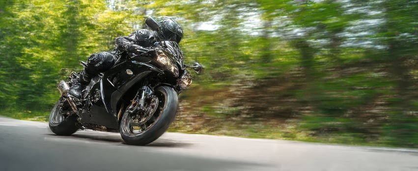 The motorcycle leaning through a forest curve at high speed on a winding road photo