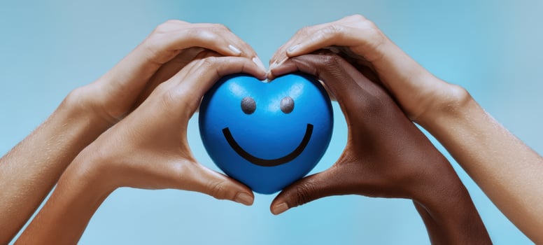 The blue smiley ball embraced by diverse hands forming a heart shaped frame photo
