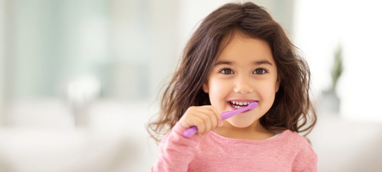 The girl brushing her teeth with a pink toothbrush in a bright bathroom photo