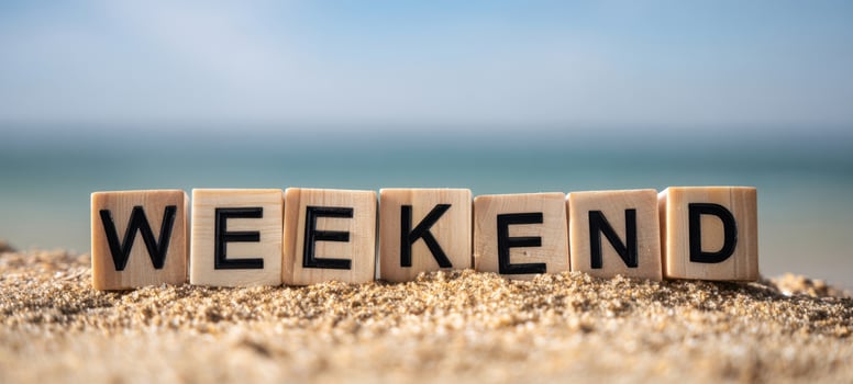 The Weekend Wooden Letter Tiles Spelled Out on Sandy Beach with Ocean Background photo