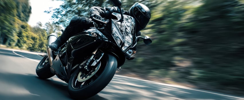 The motorcycle leaning aggressively into a high speed turn on a winding forest road photo