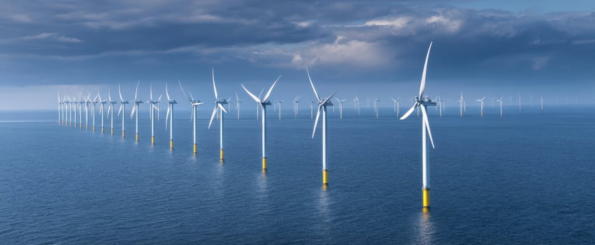 The Offshore Wind Farm Stretching Across a Dramatic Blue Sea Under Moody Storm Clouds photo