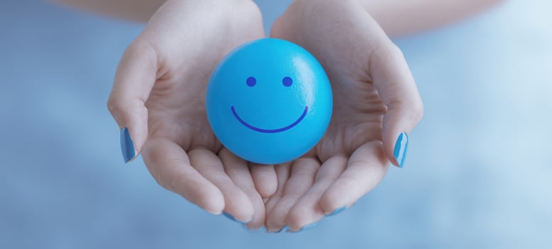 The blue smiley stress ball cradled in gentle hands conveying calm and positivity photo