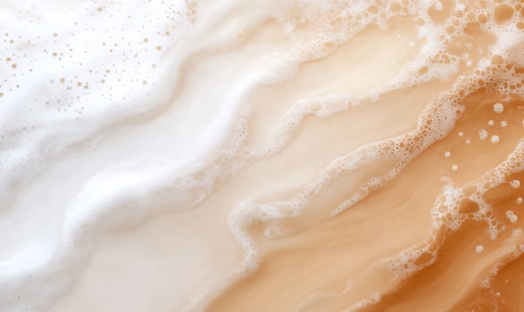 Creamy foam texture, swirling beige and white. Background blurred. Cosmetic or food use photo