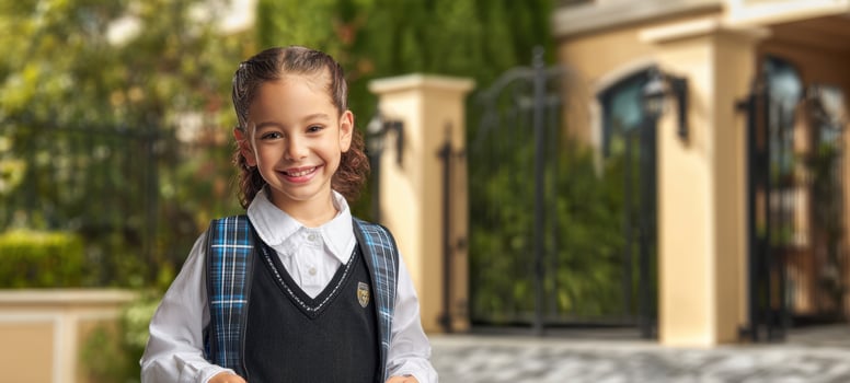 The Schoolgirl Smiling Outside Elegant School Entrance Wearing Uniform and Backpack photo