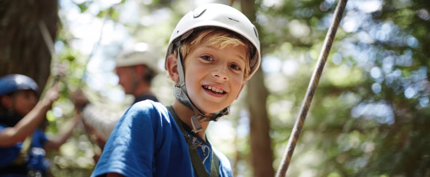 The Boy Wearing a Helmet Enjoying an Outdoor Rope Climbing Adventure in Sunlit Forest photo