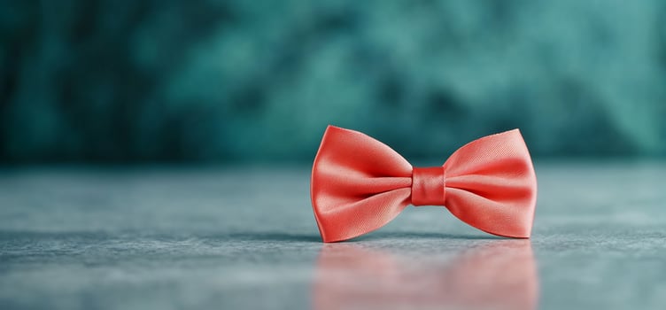 Coral bow tie on table, teal background photo