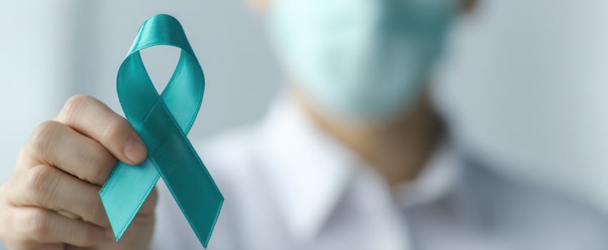 The teal awareness ribbon held by masked healthcare professional in clinic photo