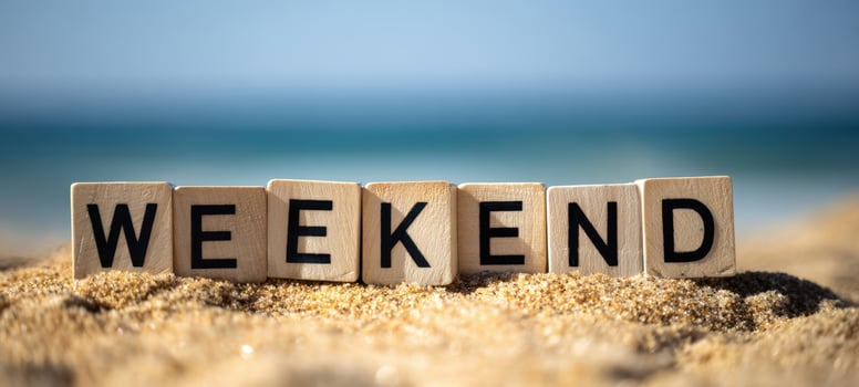 The wooden blocks spelling WEEKEND on a sunny sandy beach with ocean photo