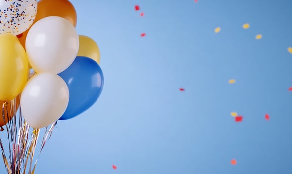 Colorful balloons floating against a blue backdrop with confetti falling photo