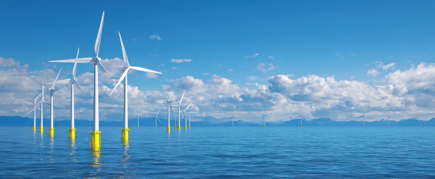 The offshore wind turbines stretching across calm ocean under bright blue sky and clouds photo