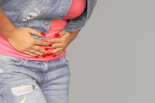 Bellyache European woman pain in the abdomen isolated on grey background photo
