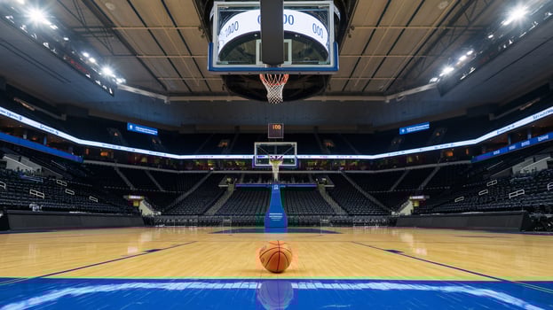 An empty basketball court features a basketball at center stage and bright stadium lights illuminating the arena. photo