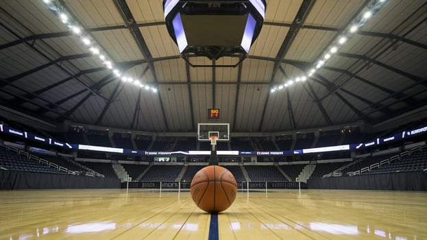 A basketball sits at center court in a spacious indoor arena, highlighting the vibrant atmosphere for sports. photo