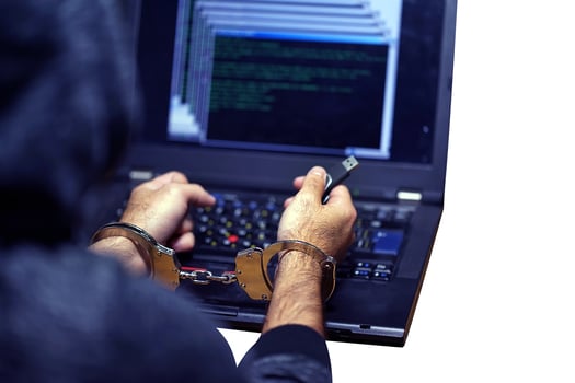 Criminal hacker hands locked in handcuffs isolated on a white background. Close-up view photo