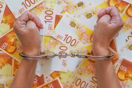 Hands of woman in office with handcuffs on Israeli money background photo